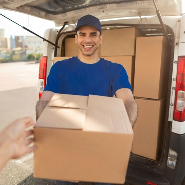 A smiling delivery worker unloading boxes from a cargo van, representing efficient freight transport up to 3.5 tons.